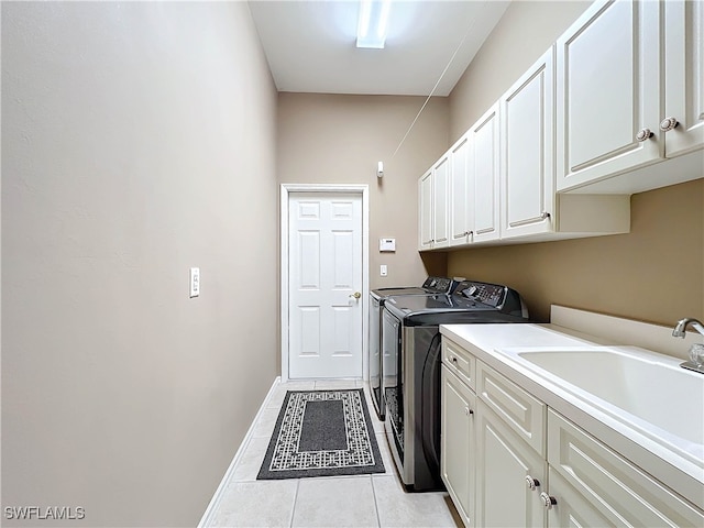 clothes washing area featuring baseboards, washing machine and dryer, light tile patterned floors, cabinet space, and a sink