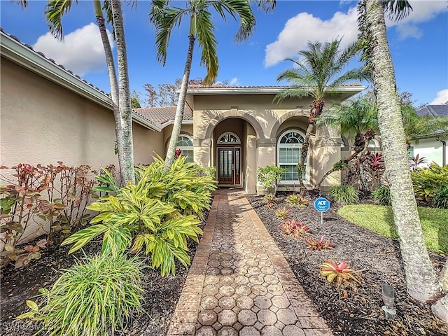 doorway to property with a tiled roof and stucco siding