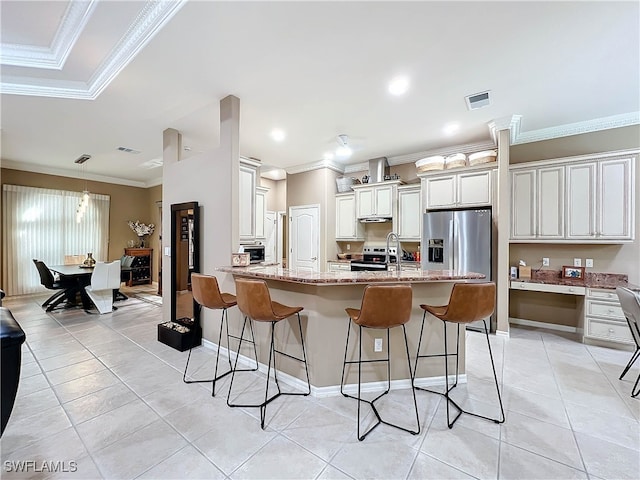 kitchen with light tile patterned floors, light stone countertops, ornamental molding, appliances with stainless steel finishes, and a breakfast bar area