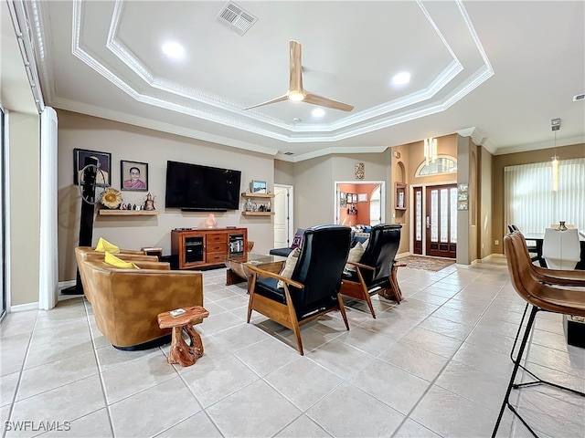 living area with visible vents, ornamental molding, light tile patterned floors, a raised ceiling, and ceiling fan