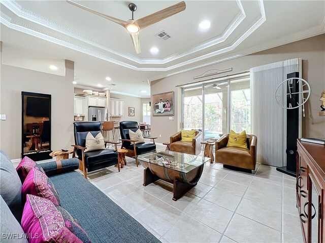 living area featuring visible vents, a tray ceiling, recessed lighting, crown molding, and light tile patterned floors