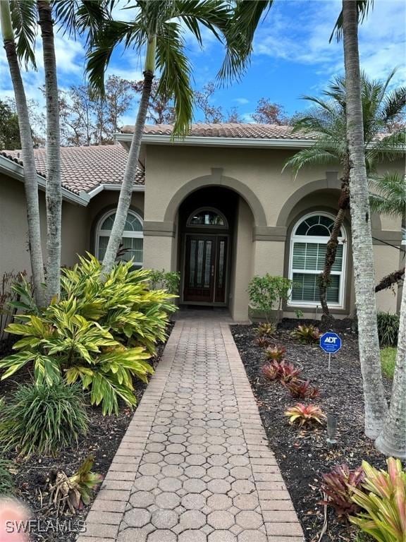 view of exterior entry featuring stucco siding and a tile roof