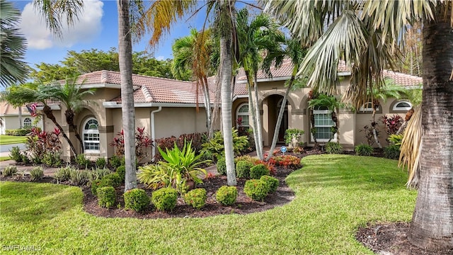 mediterranean / spanish-style home with stucco siding, a tiled roof, and a front yard