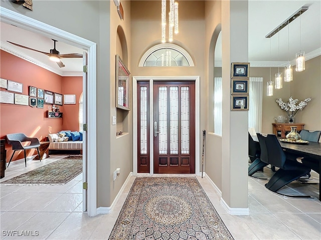 foyer entrance with arched walkways, plenty of natural light, light tile patterned flooring, and ornamental molding