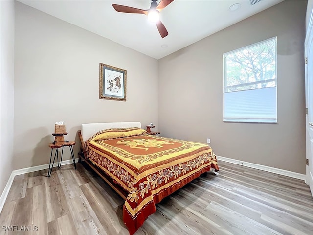 bedroom featuring visible vents, baseboards, light wood-type flooring, and ceiling fan