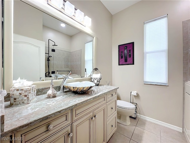 bathroom with tile patterned floors, a wealth of natural light, vanity, and a tile shower