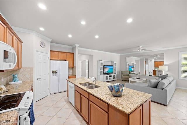 kitchen with backsplash, a kitchen island with sink, ornamental molding, sink, and white appliances