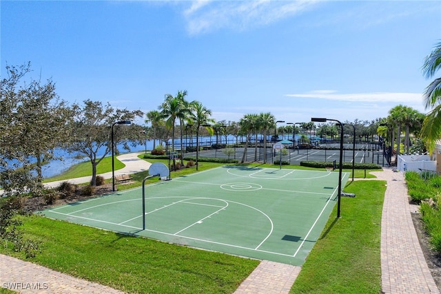 view of sport court with a water view, a lawn, and tennis court