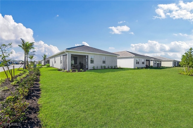 back of property with a sunroom and a lawn