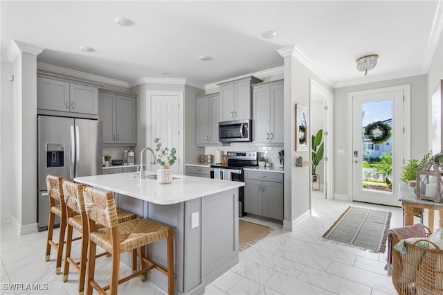 kitchen featuring a kitchen breakfast bar, stainless steel appliances, sink, and gray cabinets