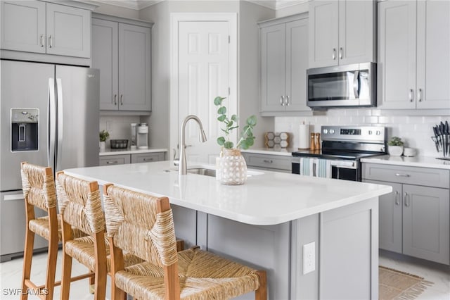 kitchen with appliances with stainless steel finishes, sink, a center island with sink, and a kitchen breakfast bar