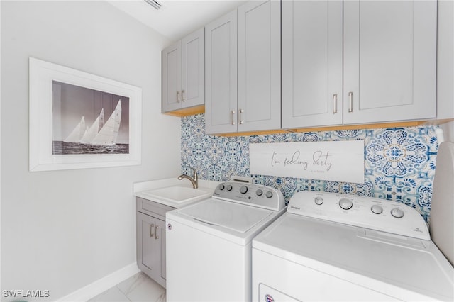 clothes washing area with cabinets, sink, and washer and clothes dryer