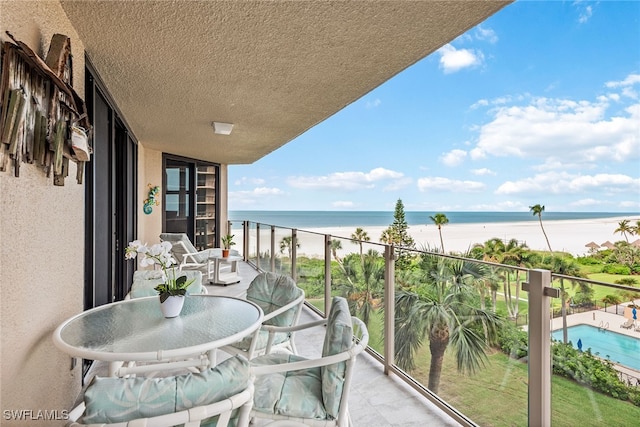 balcony featuring a view of the beach and a water view