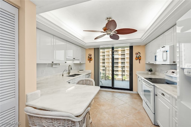 kitchen with white cabinets, a raised ceiling, ornamental molding, sink, and white appliances