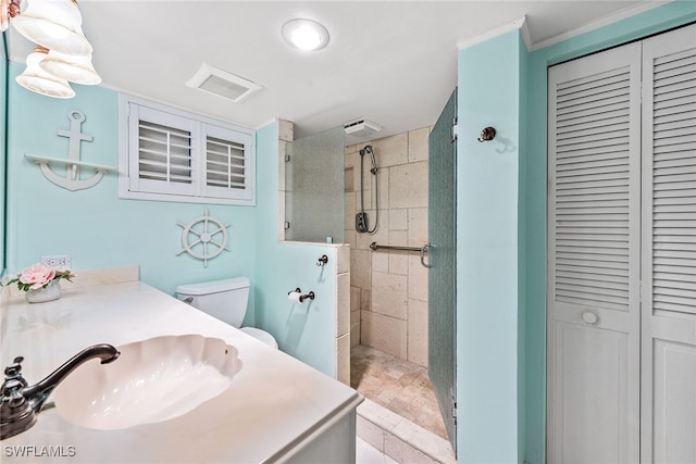 bathroom with a tile shower, toilet, and vanity