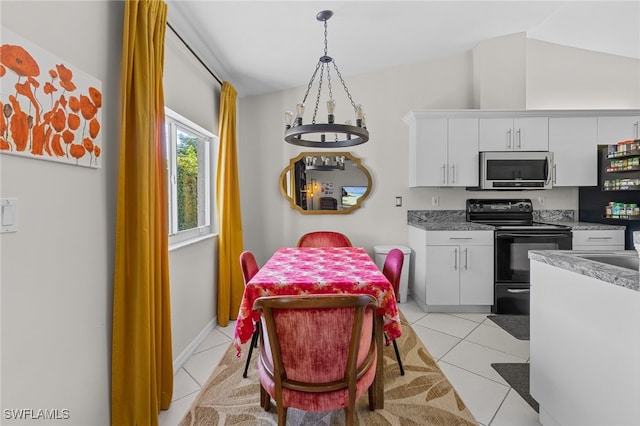 kitchen with black appliances, hanging light fixtures, lofted ceiling, white cabinets, and light tile patterned floors