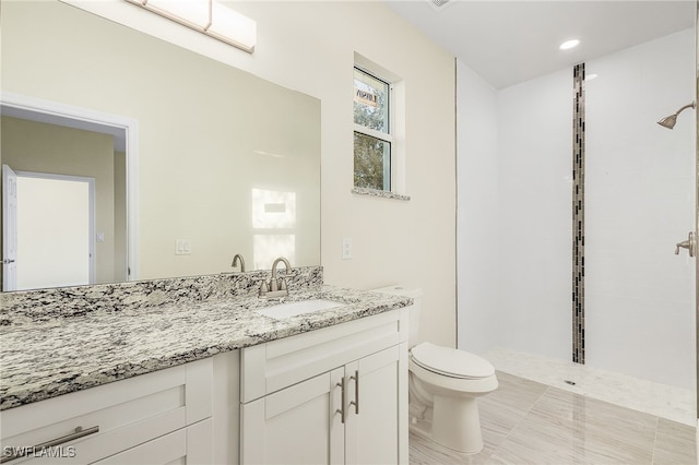 bathroom with vanity, tiled shower, toilet, and tile patterned floors