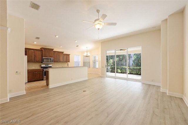 kitchen featuring backsplash, pendant lighting, a kitchen island, ceiling fan with notable chandelier, and appliances with stainless steel finishes