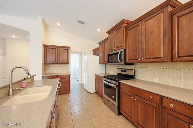 kitchen featuring backsplash, sink, vaulted ceiling, light tile patterned floors, and appliances with stainless steel finishes