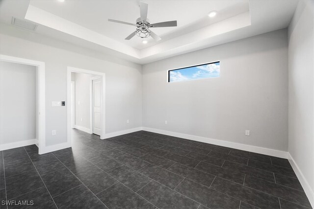 tiled spare room with ceiling fan and a raised ceiling