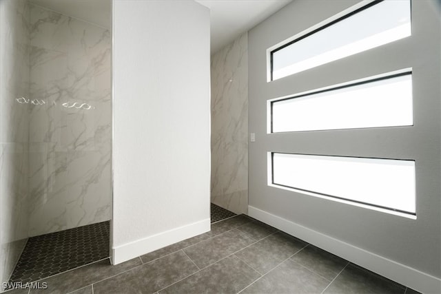 bathroom with a tile shower and tile patterned flooring