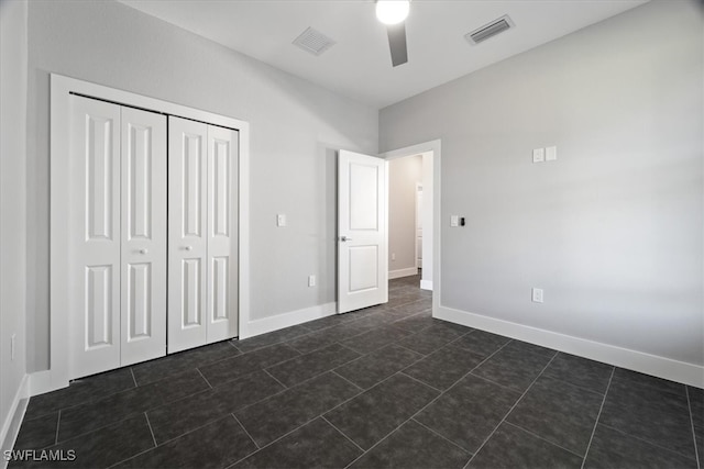 unfurnished bedroom featuring a closet, dark tile patterned flooring, and ceiling fan