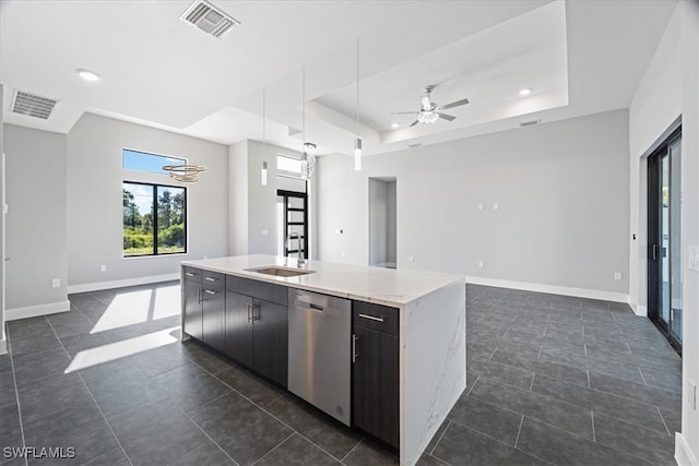 kitchen featuring sink, dishwasher, an island with sink, and a raised ceiling