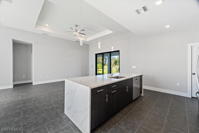 kitchen featuring a tray ceiling, dark brown cabinets, sink, and a center island with sink