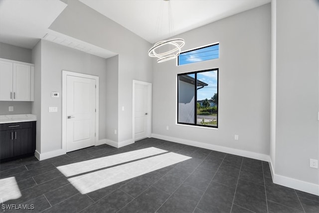 unfurnished dining area featuring dark tile patterned floors and a chandelier