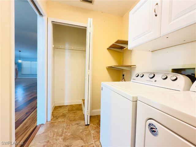 clothes washing area with light hardwood / wood-style flooring, washing machine and clothes dryer, and cabinets