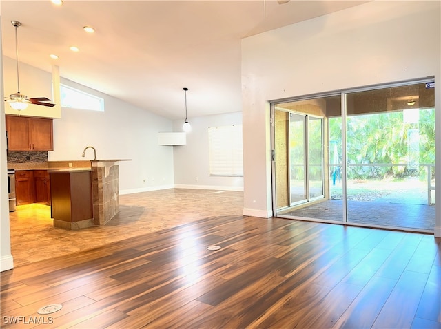 unfurnished living room featuring ceiling fan, sink, vaulted ceiling, and dark hardwood / wood-style flooring