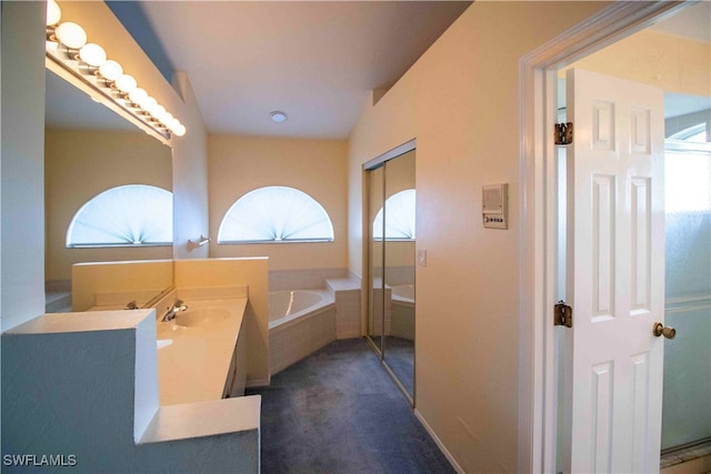 bathroom featuring vanity and a relaxing tiled tub