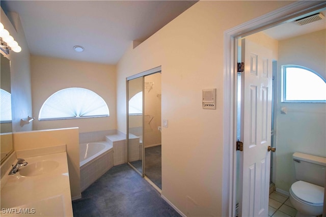 bathroom with vanity, toilet, a relaxing tiled tub, and a wealth of natural light