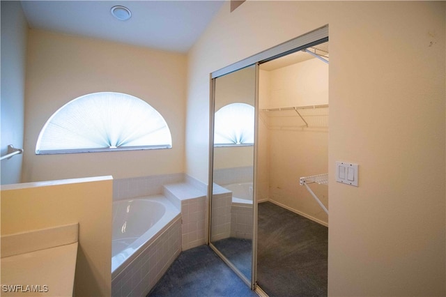 bathroom featuring vaulted ceiling and tiled tub