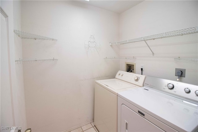 laundry room with independent washer and dryer and light tile patterned floors