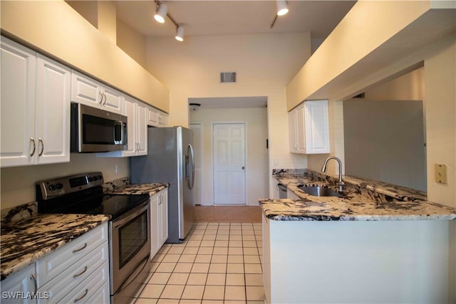 kitchen with appliances with stainless steel finishes, sink, stone countertops, rail lighting, and white cabinets