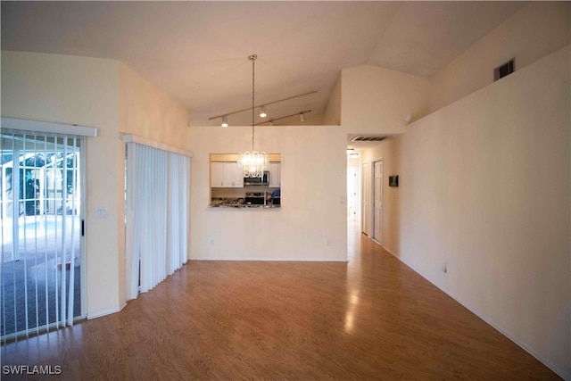 unfurnished living room with high vaulted ceiling, a chandelier, and dark wood-type flooring