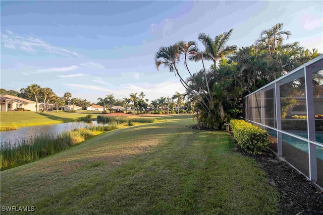 view of yard with a water view and a lanai