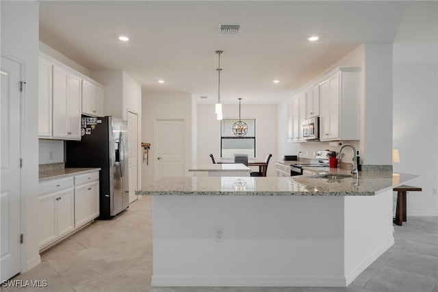 kitchen with sink, hanging light fixtures, white cabinetry, stainless steel appliances, and light stone counters