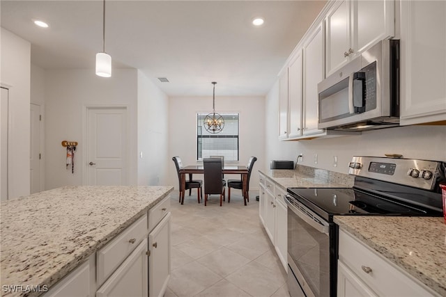 kitchen featuring light stone counters, appliances with stainless steel finishes, hanging light fixtures, and white cabinetry