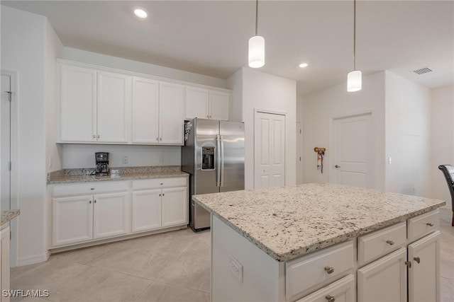 kitchen with stainless steel fridge, light stone countertops, a center island, pendant lighting, and white cabinets