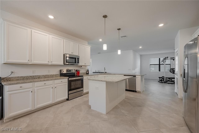 kitchen featuring stainless steel appliances, light stone countertops, a center island, pendant lighting, and white cabinets