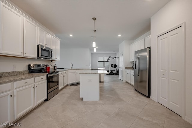 kitchen with a kitchen island, decorative light fixtures, light stone counters, and stainless steel appliances