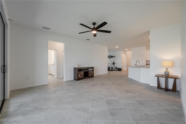 unfurnished living room featuring sink, light tile patterned floors, and ceiling fan