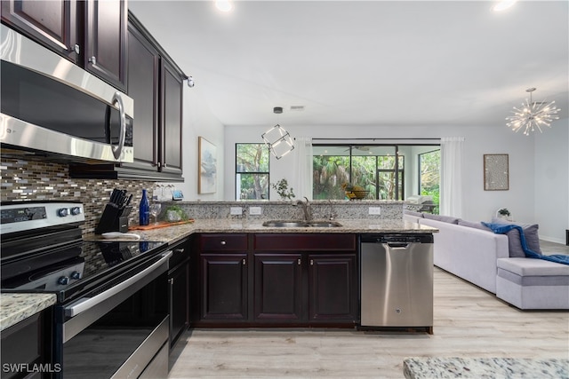 kitchen featuring appliances with stainless steel finishes, sink, light wood-type flooring, and hanging light fixtures