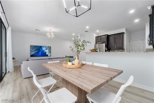 dining area with light hardwood / wood-style floors and a chandelier