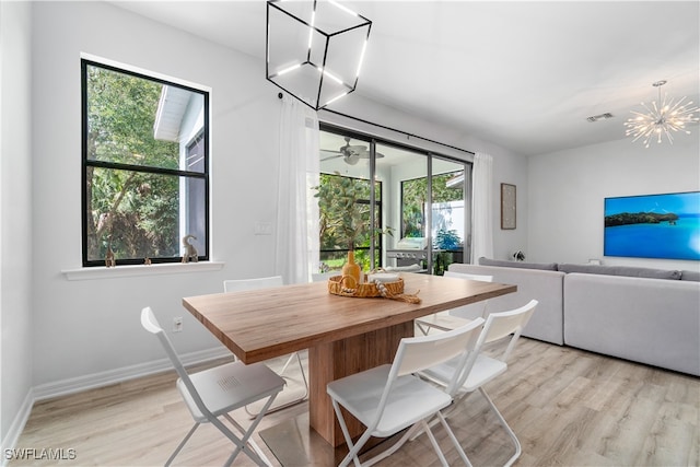 dining area with light hardwood / wood-style flooring and ceiling fan with notable chandelier