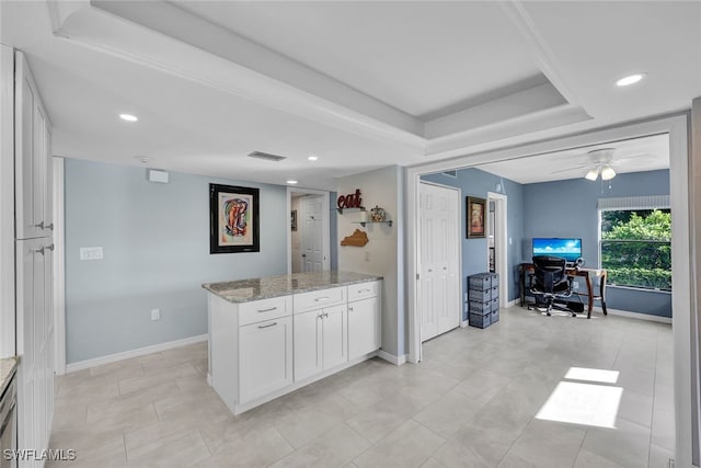 kitchen featuring white cabinets, light stone countertops, a raised ceiling, and ceiling fan