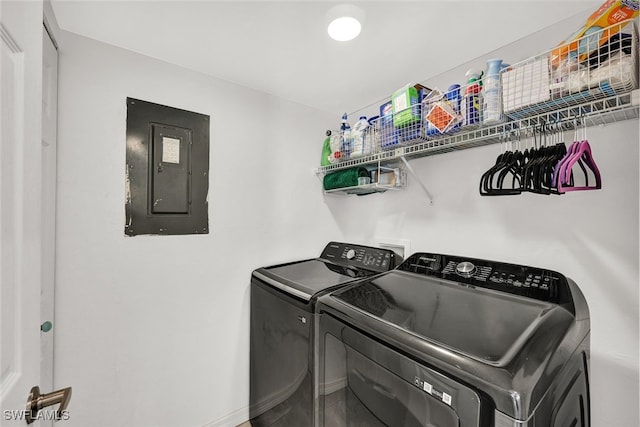 clothes washing area featuring laundry area, electric panel, baseboards, and washing machine and clothes dryer