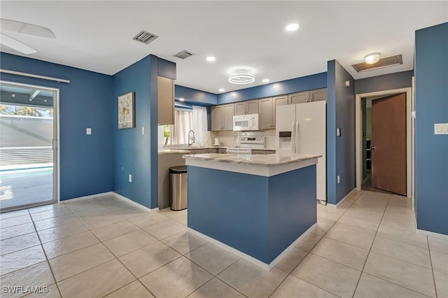 kitchen featuring a center island, light tile patterned flooring, white appliances, and sink